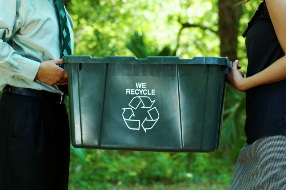 green recycling bin held by two people